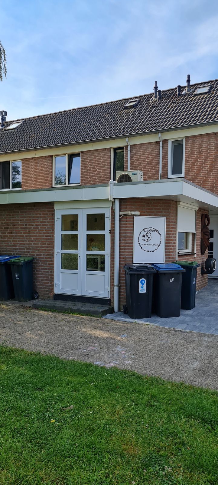 De ingang van de salon met het ronde logobordje naast de witte deuren